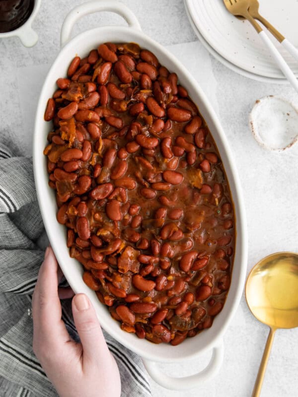 overhead view of a hand grabbing a bowl of instant pot bbq baked beans.