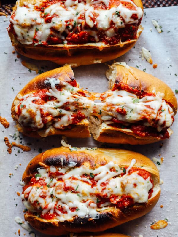 overhead view of meatball subs on a lined baking sheet, one cut in half.