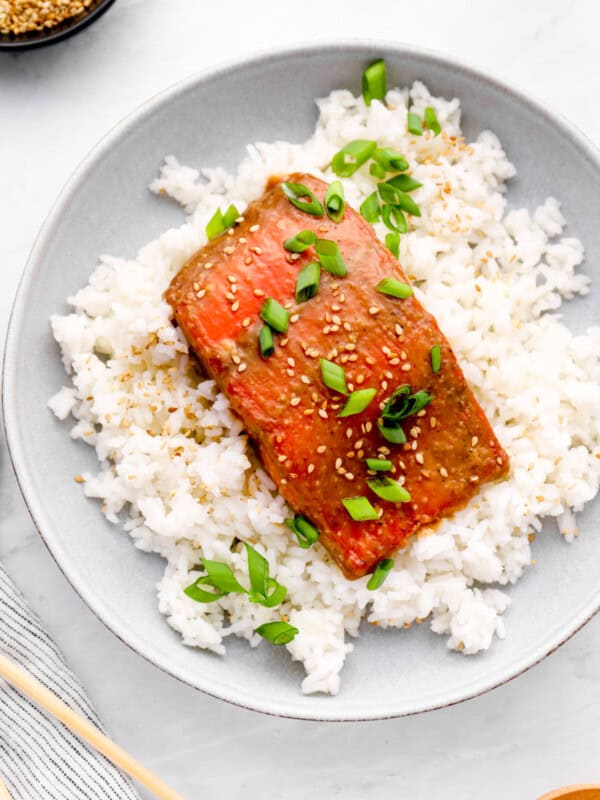 overhead view of miso glazed salmon on a bed of white rice on a white plate.