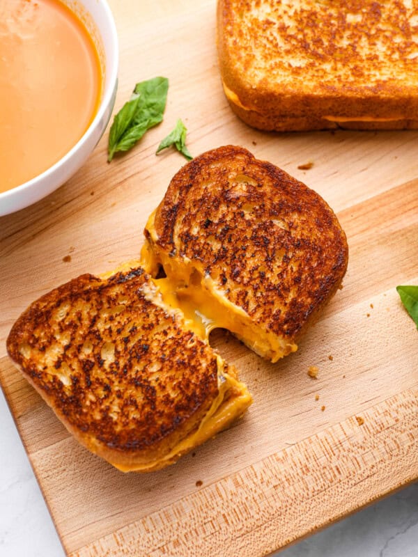 a grilled cheese cut in half on a wooden cutting board.