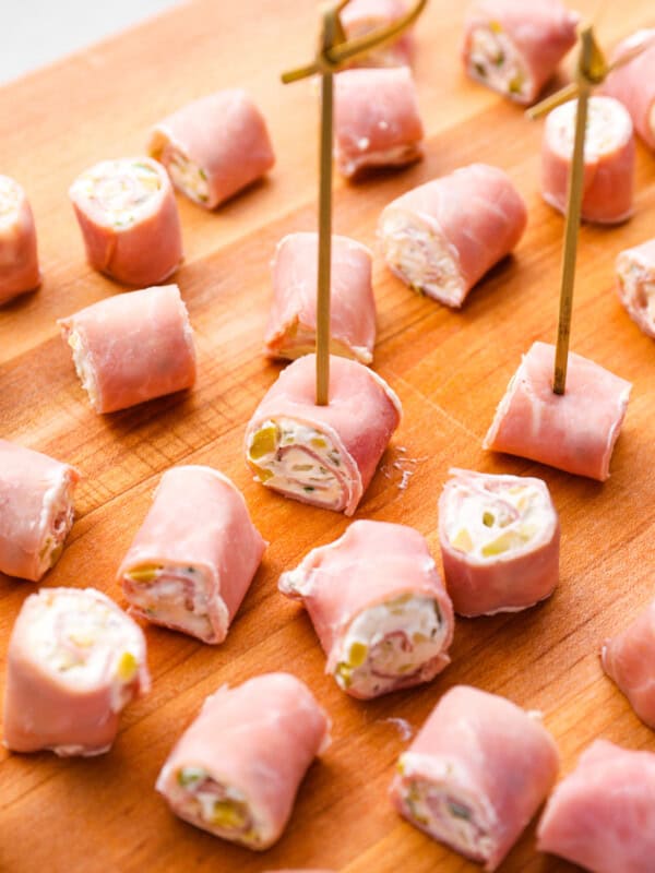 skewered ham roll ups on a wooden cutting board.