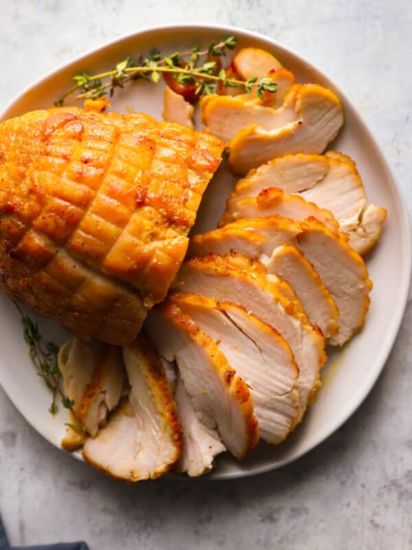 sliced honey baked turkey breast on a white serving platter.