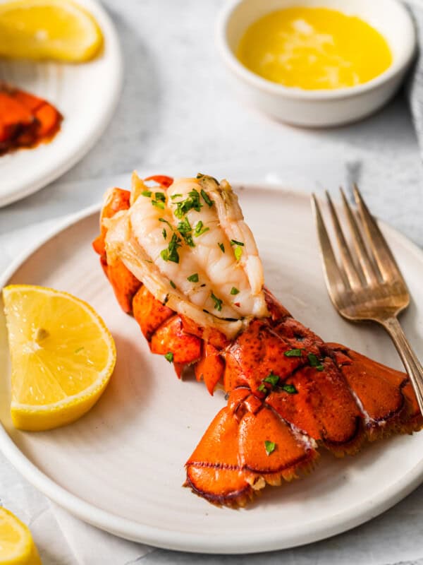 a lobster tail on a white plate with a fork and knife.