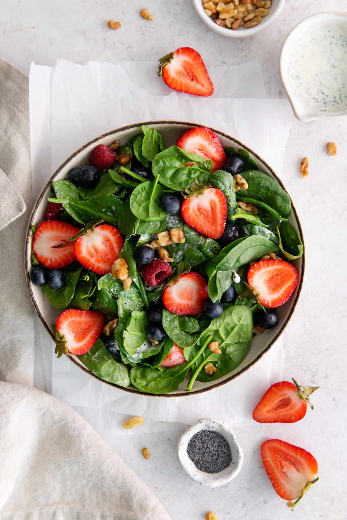 overhead view of spinach berry salad in a beige bowl.