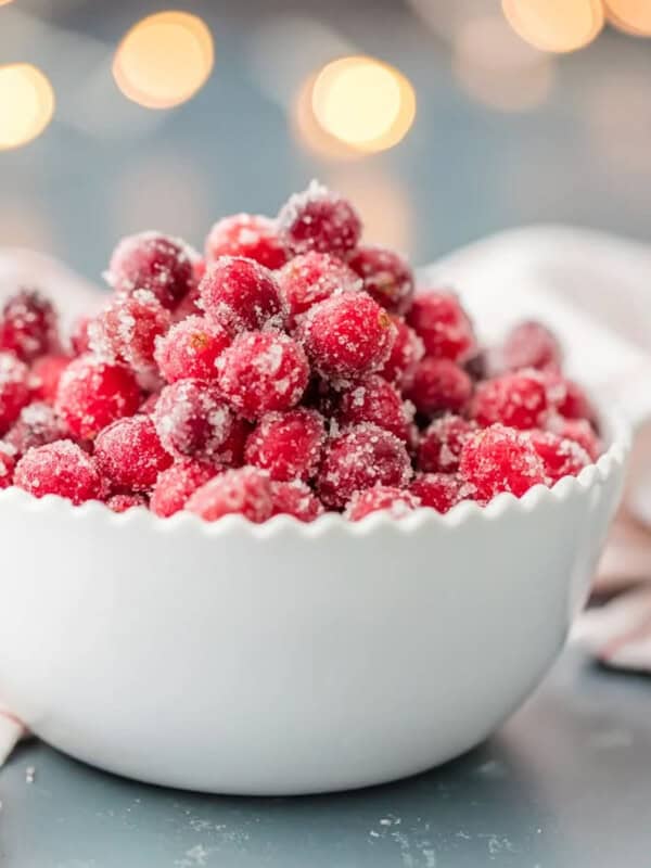 Sugared cranberries in a white bowl on a table.