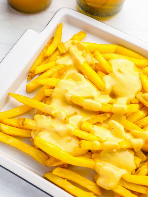 partial view of cheese fries on a white rectangular serving dish.