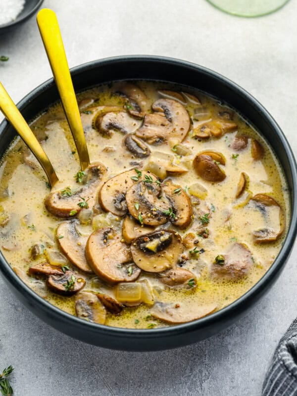 mushroom soup in a black bowl with 2 spoons.