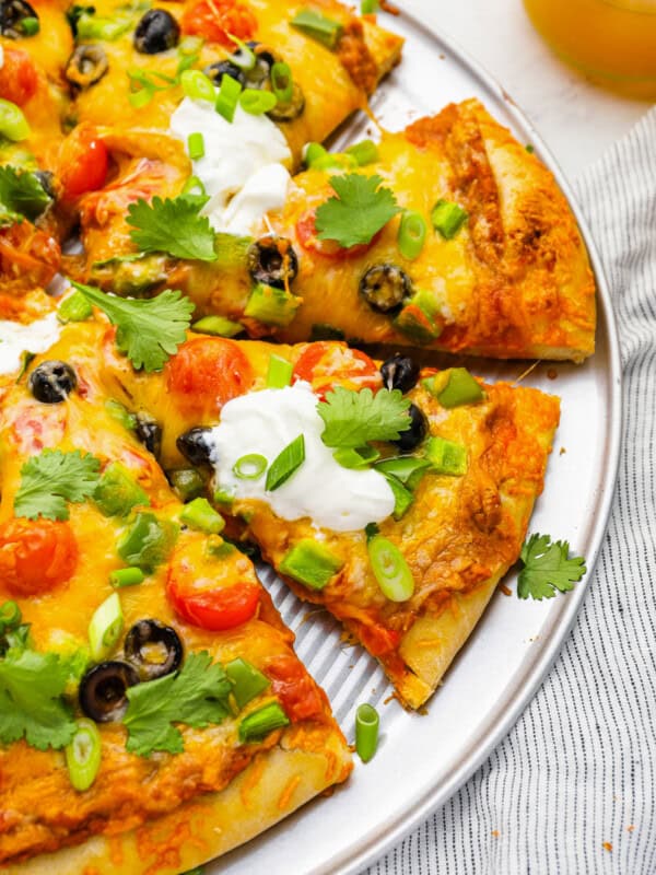 partial view of a sliced taco pizza on a pizza pan.