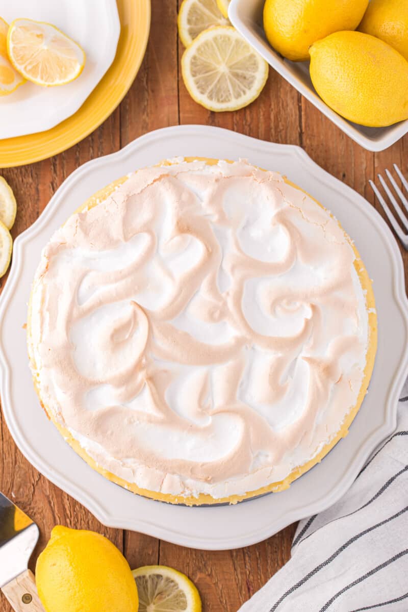overhead view of lemon meringue cheesecake on a white cake stand.