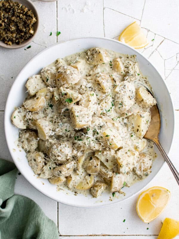 overhead view of pesto potato salad in a white bowl with a spoon.