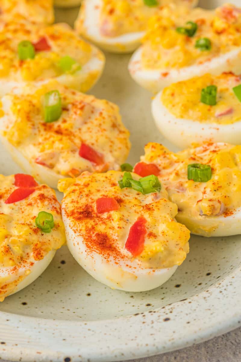 close up of pimento cheese deviled eggs on a white oval serving tray.