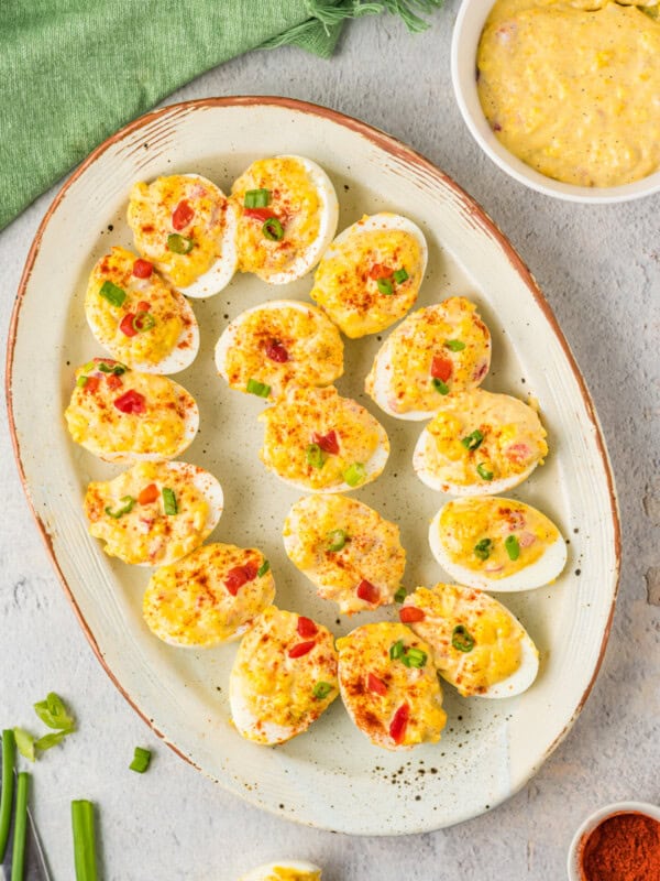 overhead view of pimento cheese deviled eggs on a white oval serving tray.