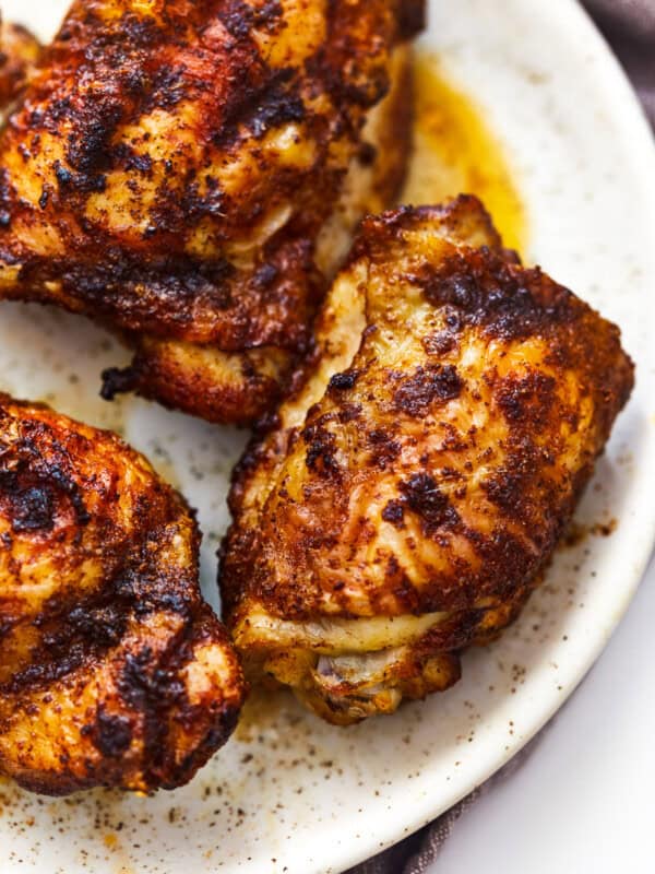 3 air fryer chicken thighs on a white plate.