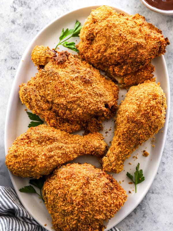 overhead view of 5 pieces of air fryer fried chicken on a white oval serving platter.