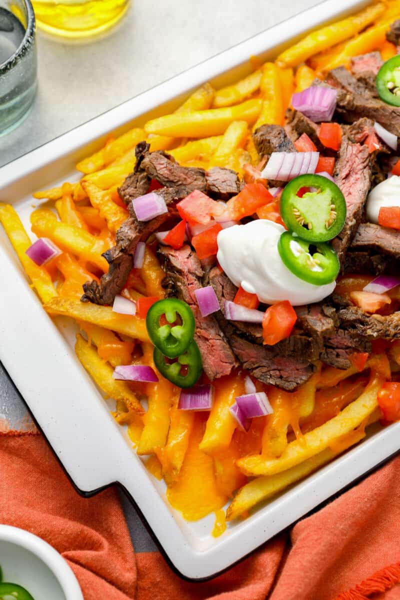 partial overhead view of fries topped with cheese, carne asana steak, jalapeños, and sour cream