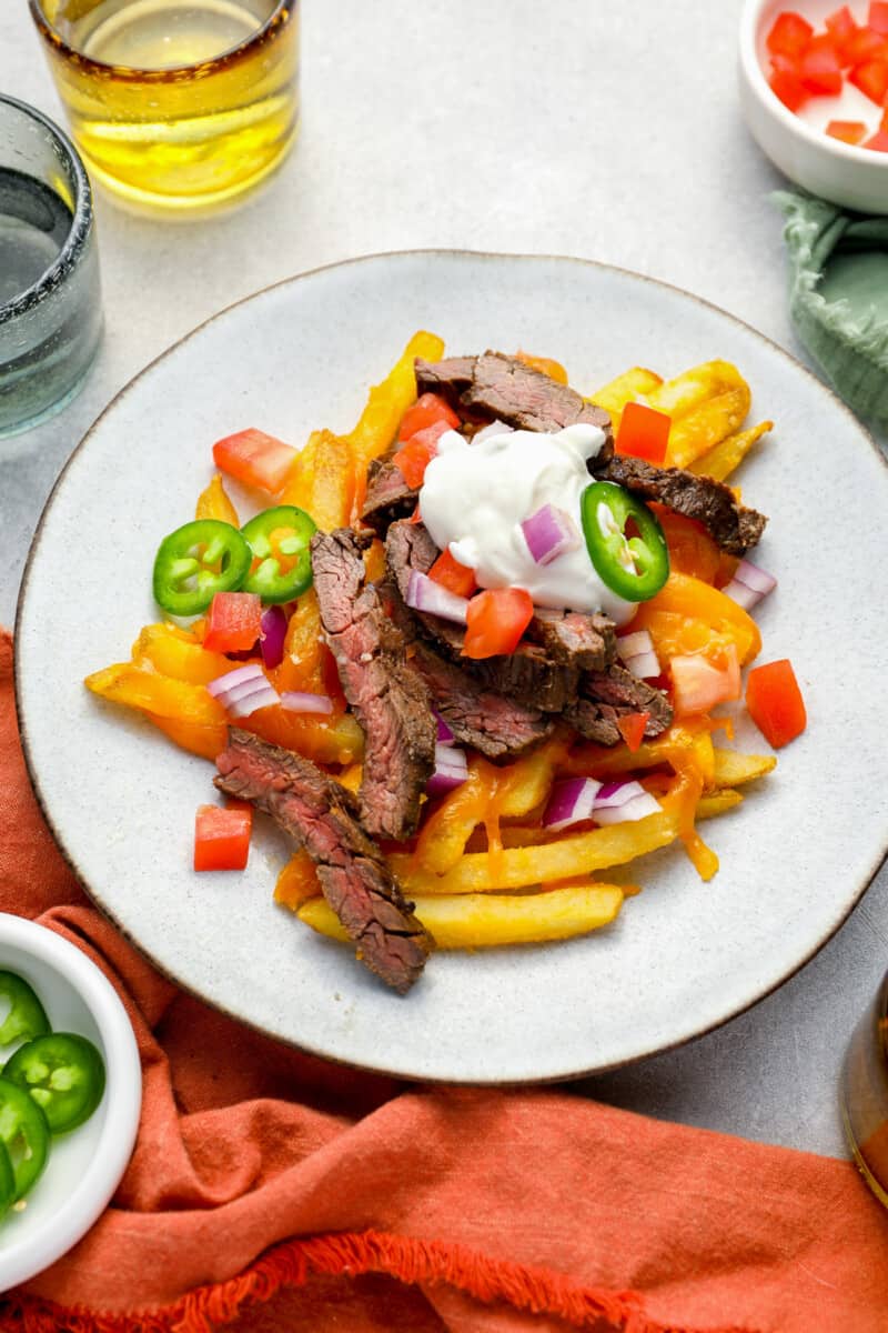 overhead view of a serving of carne asada fries on a white plate.