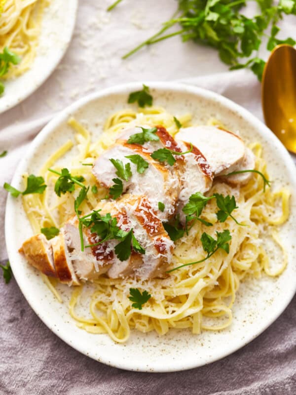 overhead view of a serving of chicken alfredo on a white plate.