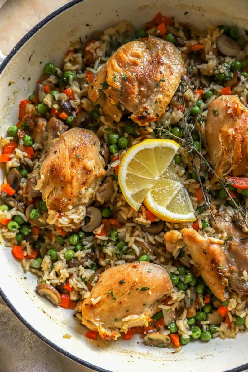 partial overhead view of chicken and rice in a dutch oven with lemon slices.