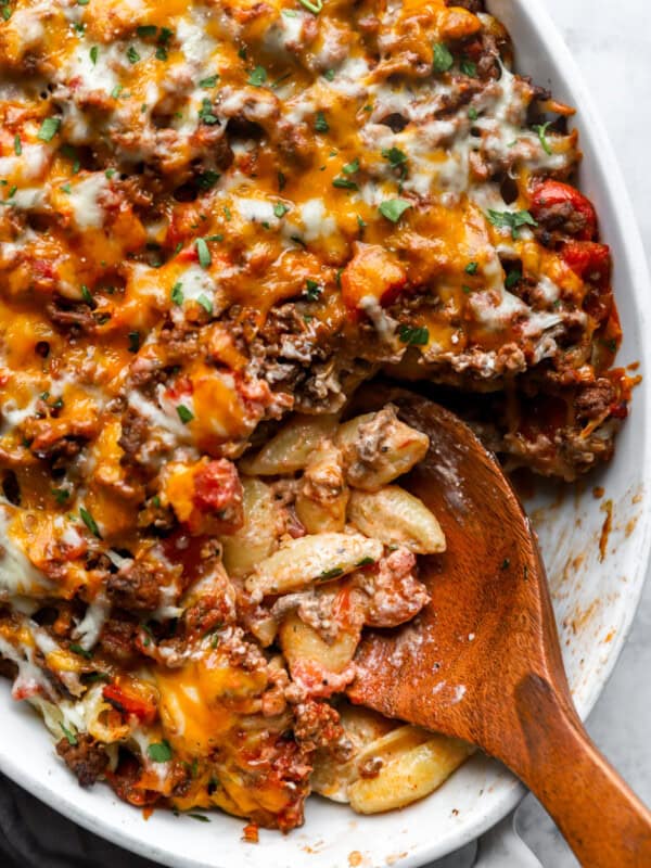 overhead view of hamburger casserole in a white oval casserole dish with a wooden spoon.