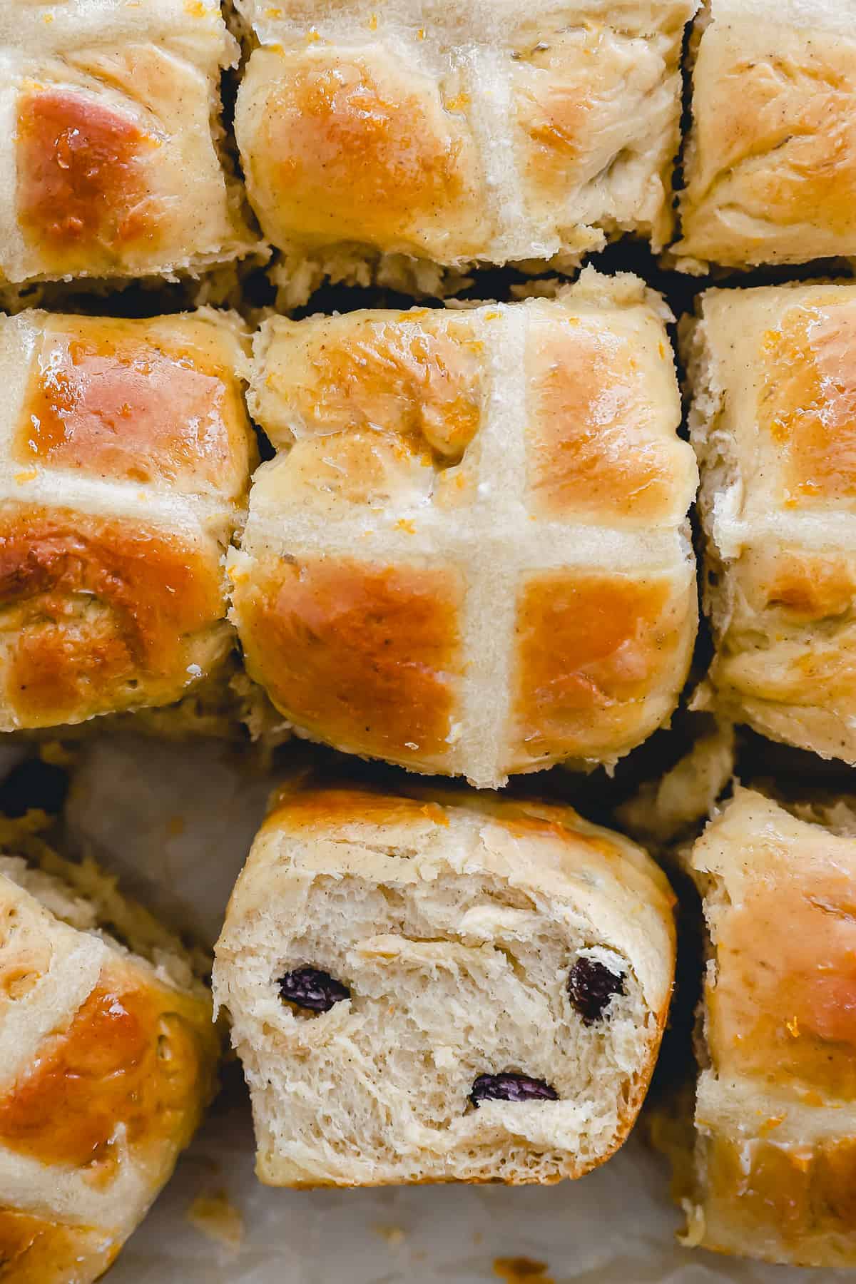 close up overhead view of hot cross buns, one turned on its side to show the texture.