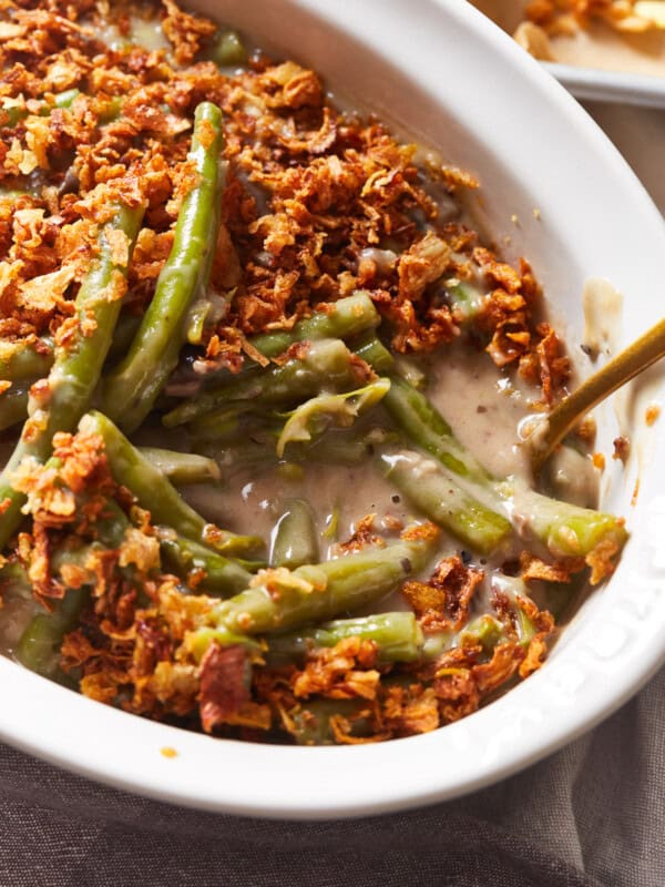 close up view of instant pot green bean casserole in a white serving dish with a spoon.