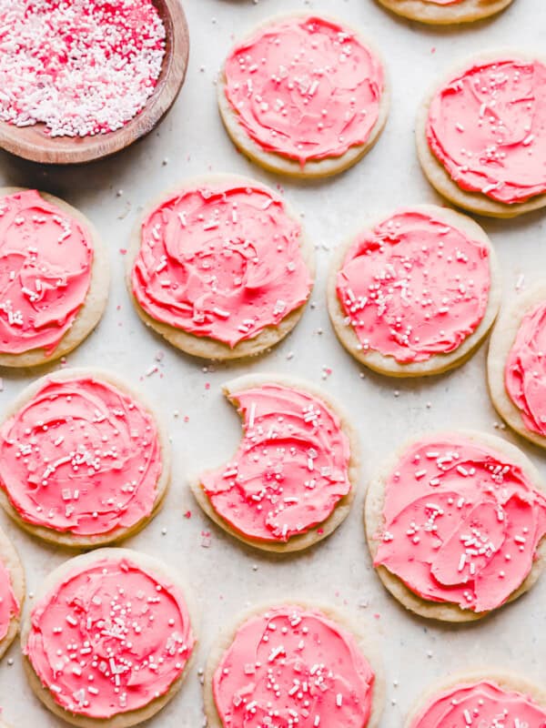 overhead view of pink frosted lofthouse cookies on parchment, one is bitten.