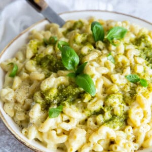 three-quarters view of a bowl of pesto mac and cheese with a fork.