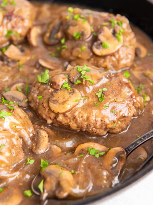 close up of salisbury steaks in a cast iron pan.