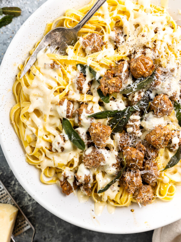 partial overhead view of fettuccini alfredo on a white plate.