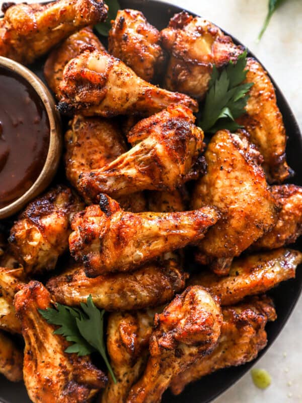 overhead view of smoked chicken wings on a black serving plate with barbecue sauce.