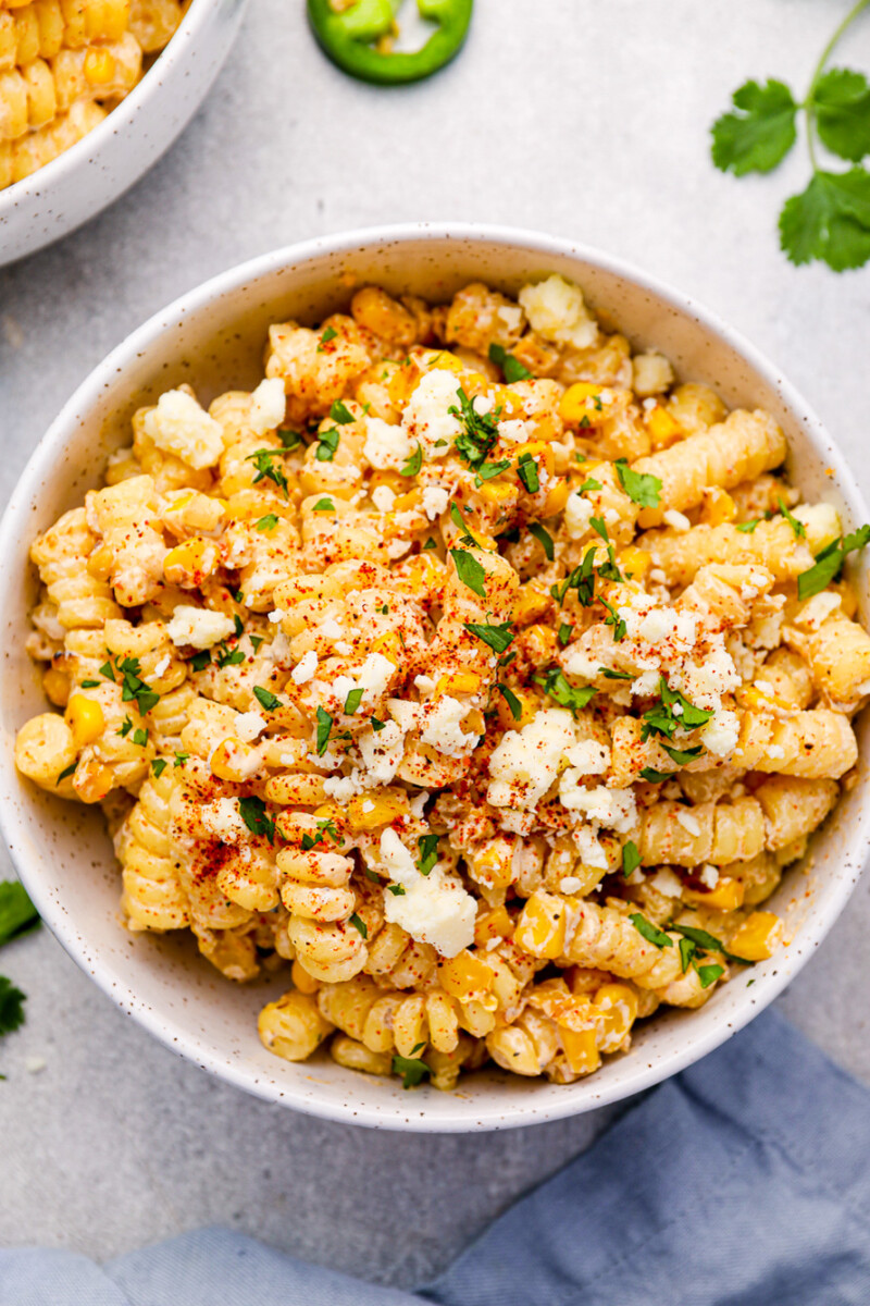 overhead view of a serving of street corn pasta salad in a white bowl.