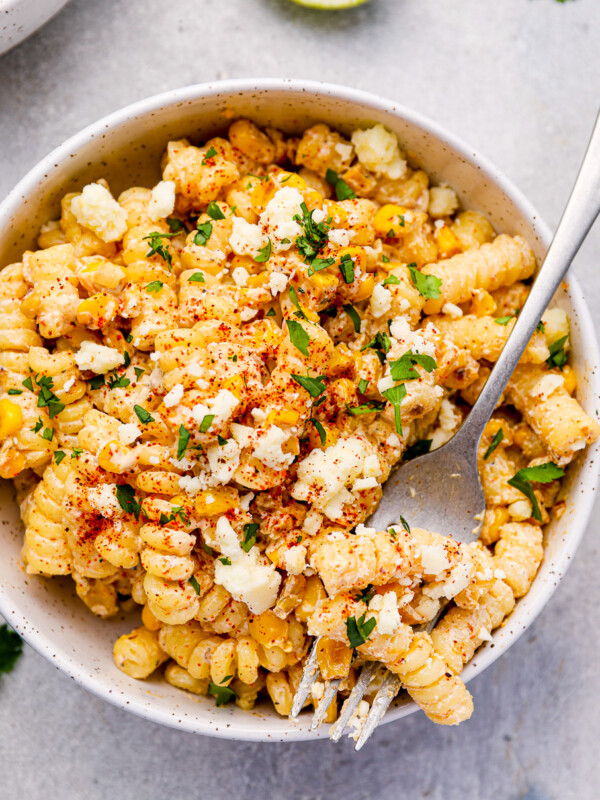 overhead view of a serving of street corn pasta salad in a white bowl with a fork.