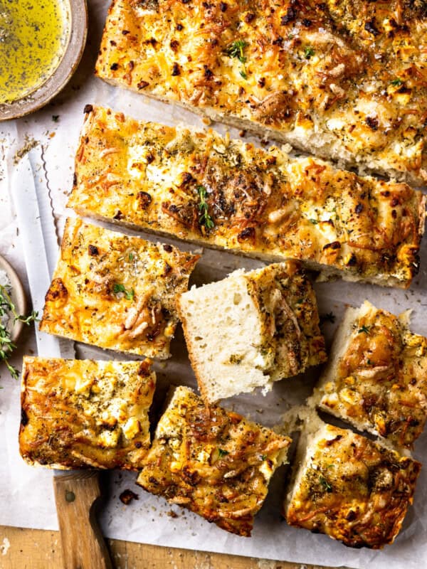 overhead view of no knead focaccia cut into squares with one upturned to show the texture.