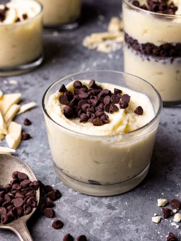 swirled white chocolate mousse in a small glass cup with chocolate chips on top.