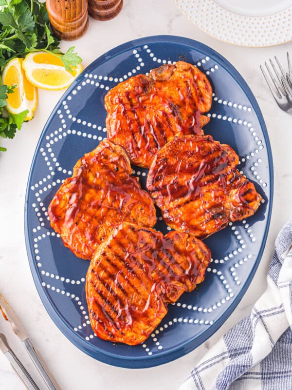 overhead view of 4 bbq pork chops on a blue plate.