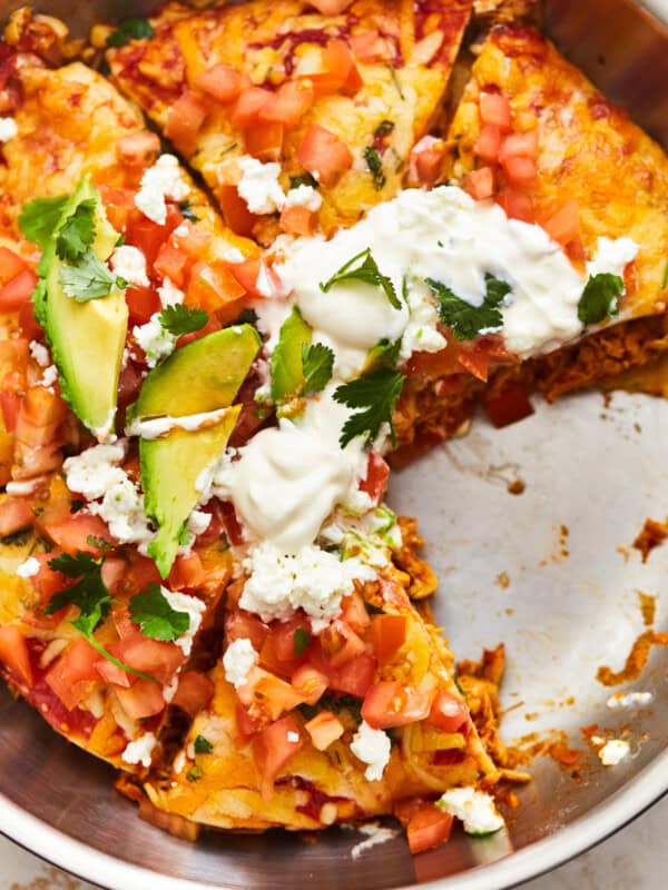 overhead view of a sliced chicken enchilada skillet in a skillet missing a slice.