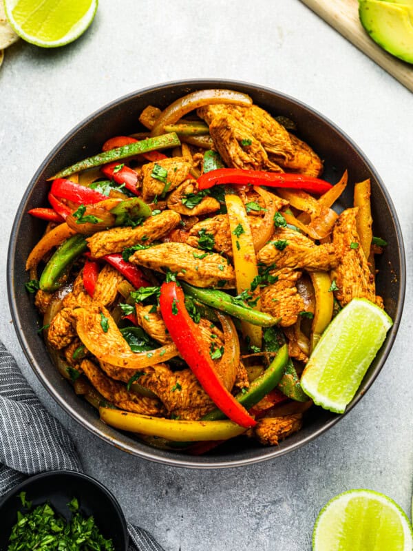 overhead view of chicken fajita filling in a black bowl with a lime wedge.