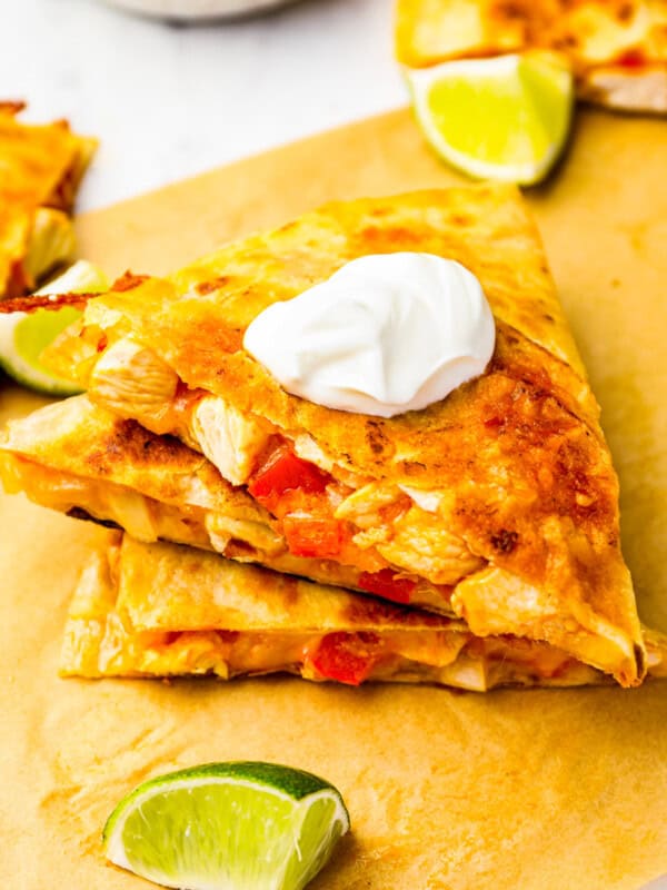 3 stacked slices of chicken quesadilla on parchment paper.