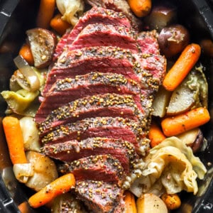 overhead view of sliced crockpot corned beef and cabbage in a crockpot.