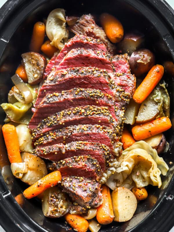 overhead view of sliced crockpot corned beef and cabbage in a crockpot.