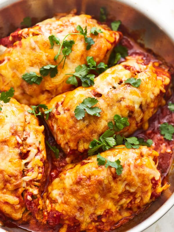 overhead view of 4 enchilada stuffed chicken breasts in a frying pan.