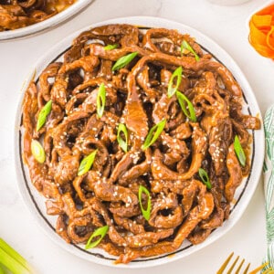 a plate of beef stir fried with sesame seeds and green onions.