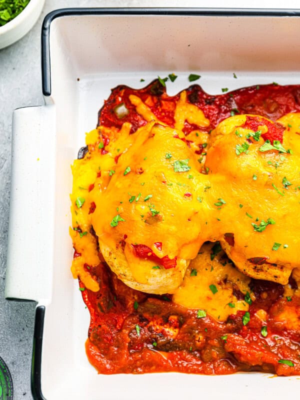 partial overhead view of baked salsa chicken in a white rectangular baking pan.