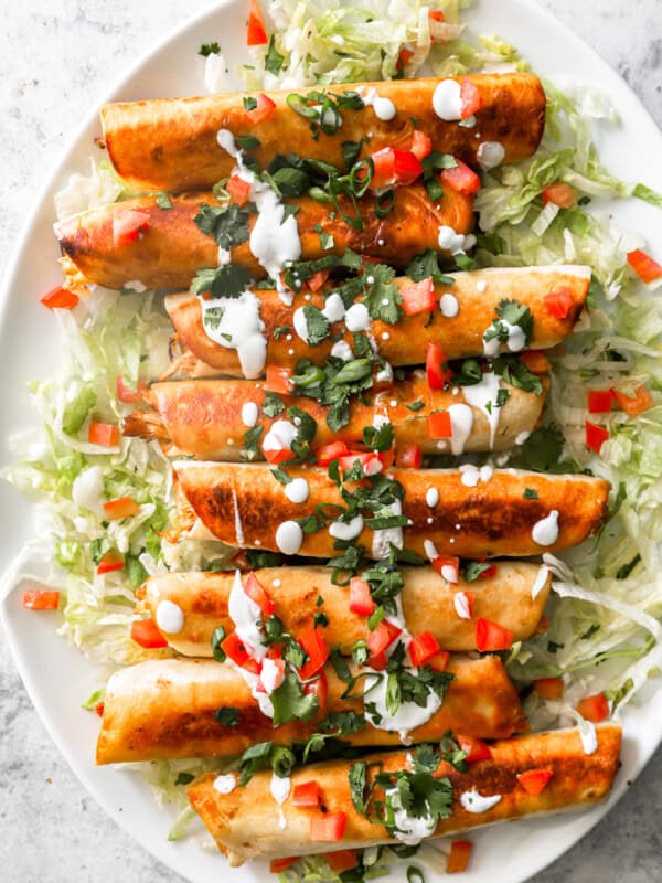 overhead view of 8 chicken flautas on an oval serving platter.