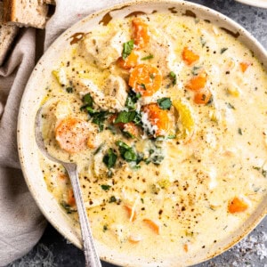 a bowl of soup with bread and carrots.