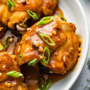 chicken thighs with sauce on a white plate.