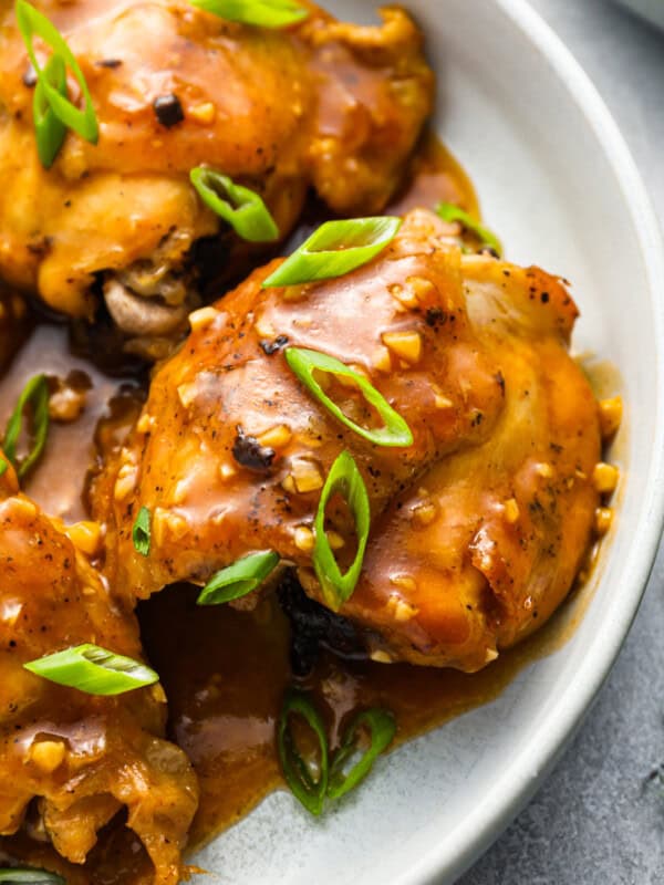 chicken thighs with sauce on a white plate.