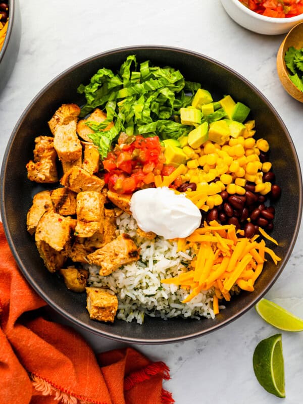 a bowl of mexican rice with chicken, corn, beans and sour cream.