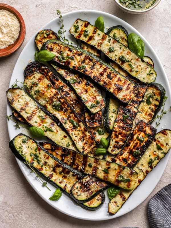 overhead view of grilled zucchini on a white oval plate.