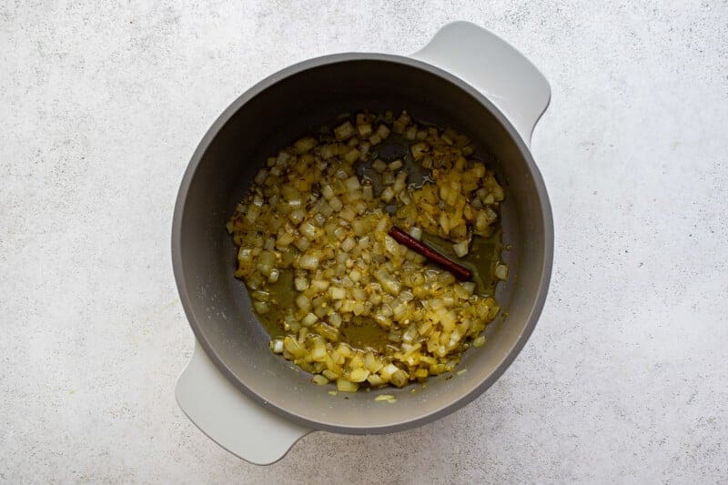 a bowl filled with onions and garlic on a white surface.